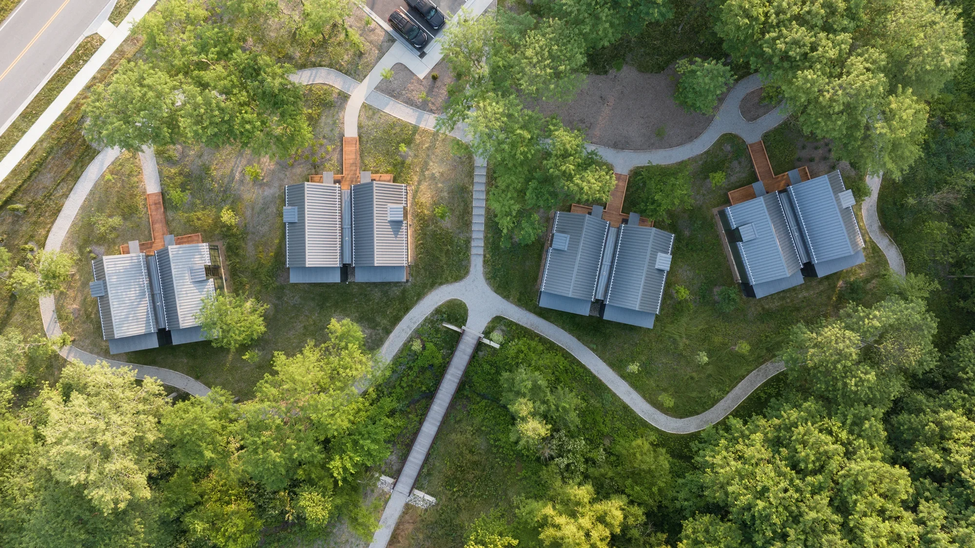 Focal Herzog Foundation Cabins (Aerial view) metal roofing wood decks forested gravel paths 