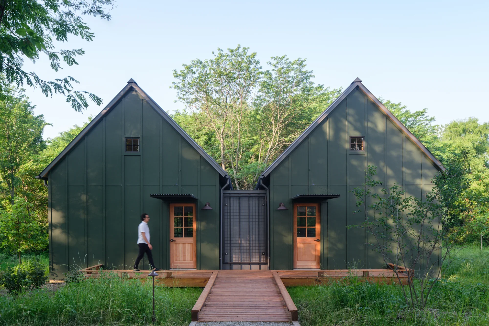 Focal Herzog Foundation Cabins symmetrical gable roofs hardi board siding wood decking entry corrugated metal surrounding forest 